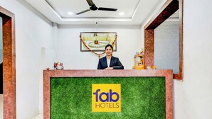 Una recepción con el logo de 'fab hotels', un ventilador de techo y un cuadro en la pared.