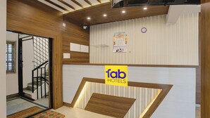 A hotel reception area with a wooden reception desk, a clock, and a calendar on the wall. - FabHotel Purple Grand - Jalahalli West (Bangalore)