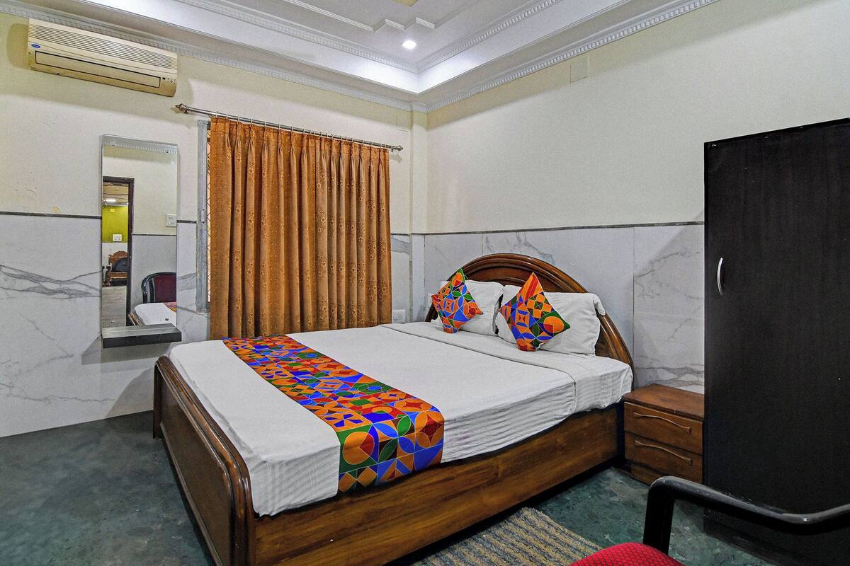 A hotel room with a wooden bed, a black wardrobe, and a mirror on the wall.