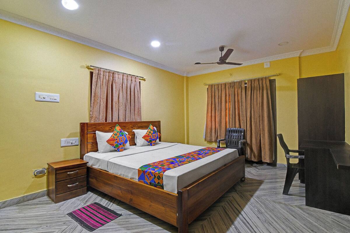 A bedroom with a wooden bed, a nightstand, a desk, a chair, and a ceiling fan.