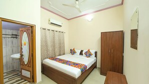 A bedroom with a bed, a wardrobe, a bedside table, a ceiling fan, and an air conditioning unit. - Via Mansagar (Jaipur)