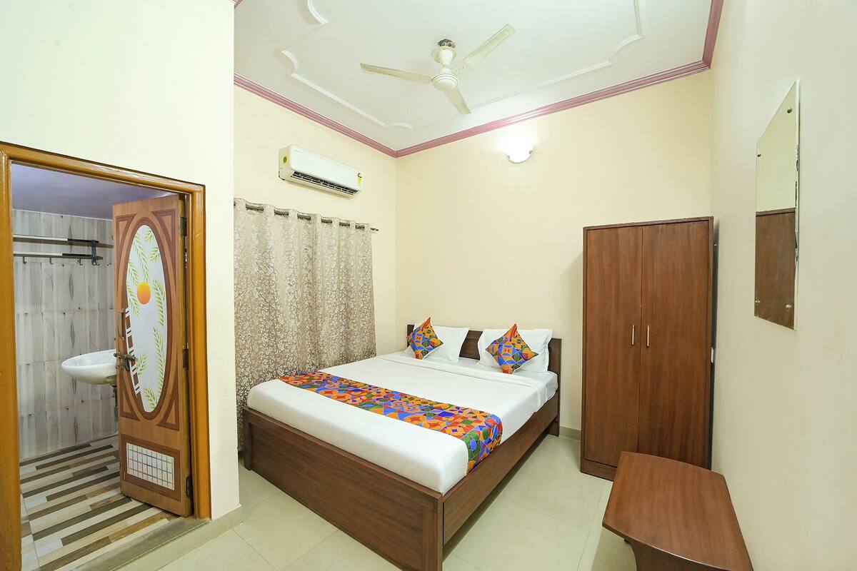 A bedroom with a bed, a wardrobe, a bedside table, a ceiling fan, and an air conditioning unit.