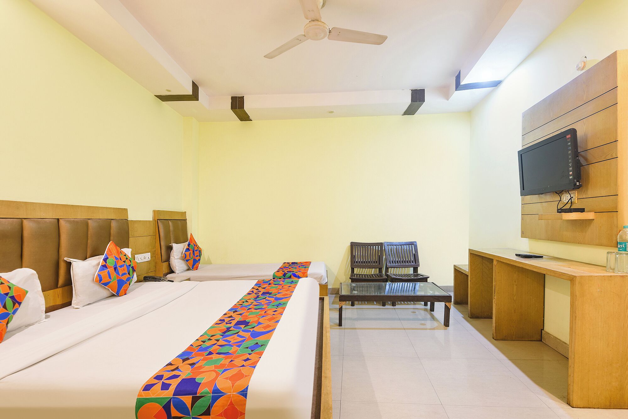 A hotel room with two beds, a TV, a desk, and a chair.
