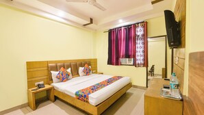 A hotel room with a bed, bedside table, and a TV mounted on the wall. - Fabhotel Golden Gate Deluxe (New Delhi)
