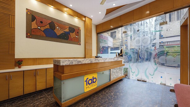 A hotel reception area with a marble counter, wooden paneling, and a large abstract painting. - Fabhotel Golden Gate Deluxe (New Delhi)