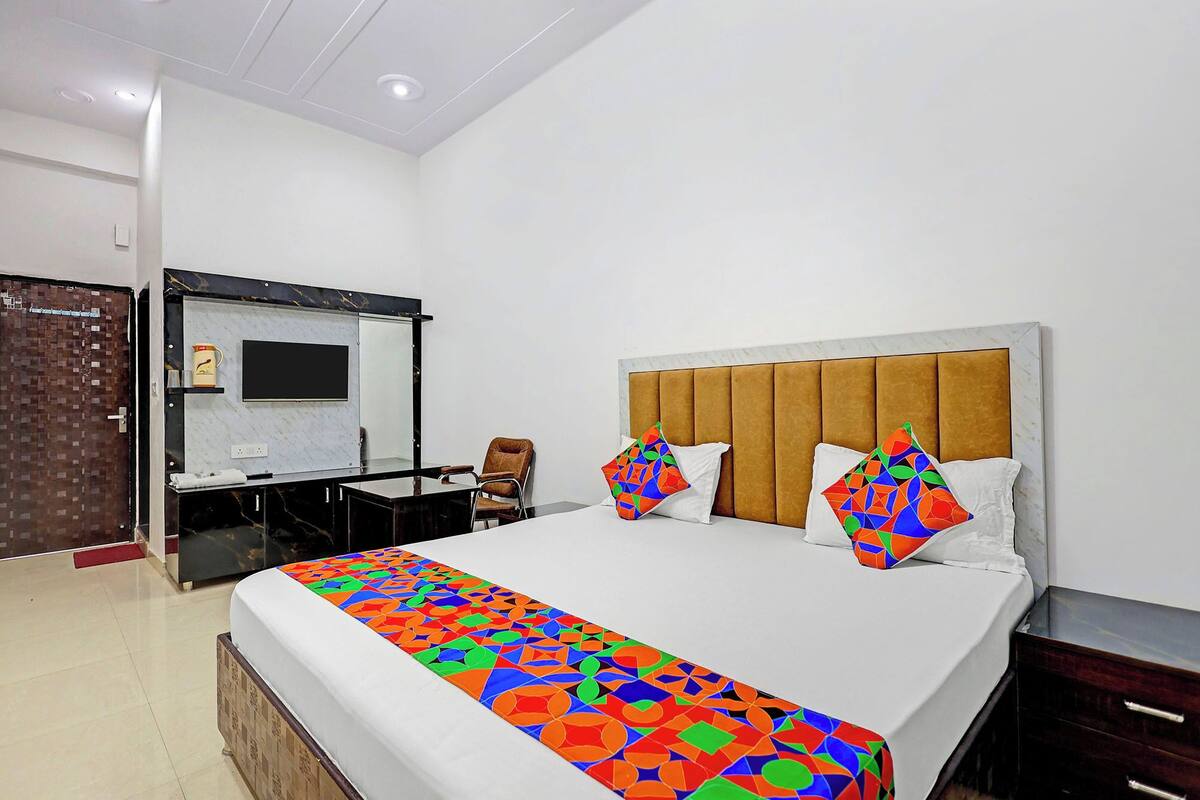 A hotel room with a bed, a desk, a chair, and a mirror.