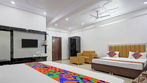 A modern hotel room with a large bed, a sofa, a small table, and a wardrobe. - Fabhotel Shri Hari Singh Dham (Vrindavan)