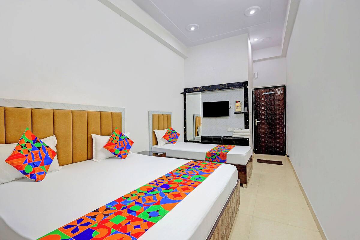 A hotel room with two beds, a large mirror, a TV, and a door with a patterned design.
