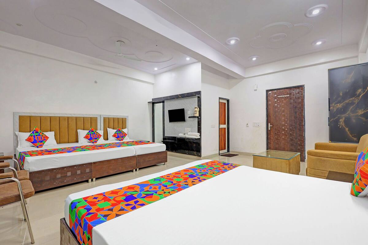A hotel room with a large bed, a smaller bed, a sofa, a TV, a bathroom, and a door with a marble design.
