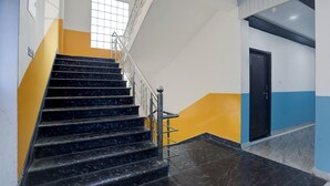 A staircase with black marble steps, metal railings, and a yellow accent wall. - Via Atithi Inn (Varanasi)
