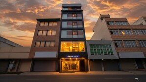 A modern hotel building with a glass facade and a sign reading "fabHOTELS". - Fabhotel Happy Stay (Noida)