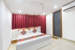 A bedroom with a bed, curtains, an air conditioning unit, and a door. - Fabhotel Happy Stay (Noida)