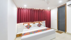 A modern hotel room with a large bed, red curtains, and a wooden headboard. - Fabhotel Happy Stay (Noida)
