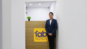 A reception desk with a logo for 'Fab Hotels' and a potted plant on top. - Fabhotel Happy Stay (Noida)