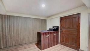 A room with a wooden desk, a closed door, and a striped wall. - Fabhotel Lorung Residency (Darjeeling)
