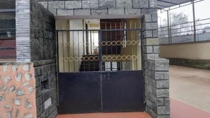 A gated entrance with a metal gate and stone walls. - Fabhotel Lorung Residency (Darjeeling)