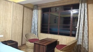 A room with a large window, a small table, two wicker chairs, and a radiator. - Fabhotel Lorung Residency (Darjeeling)