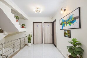 A modern hotel lobby with a staircase, two wooden doors, a large abstract painting, and potted plants. - Fabhotel Jp Palace (New Delhi)