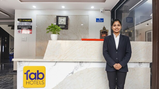 A hotel reception desk with a marble design, a clock, and a sign for J.P. Palace. - Fabhotel Jp Palace (New Delhi)
