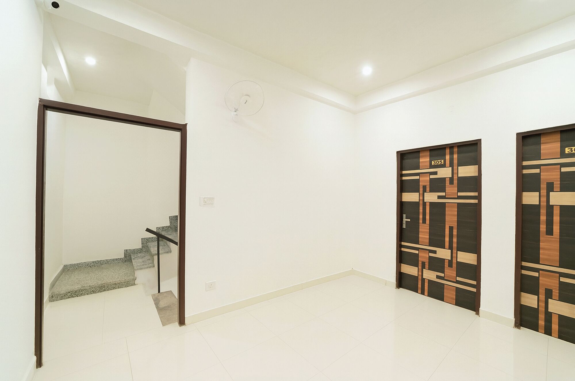 Un corridoio con una porta in vetro, una scala e due porte decorate.