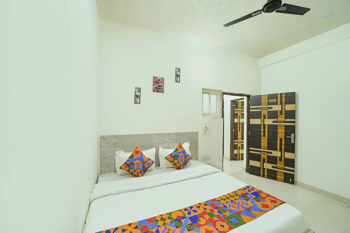 A bedroom with a bed, pillows, a ceiling fan, a door, and wall decorations.