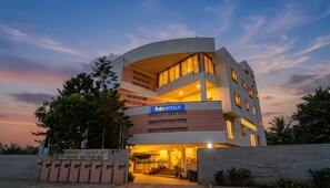 A modern hotel with a curved facade, multiple floors, and a sign for 'fabHOTELS'. - Fabhotel Jk Grand (Bangalore)