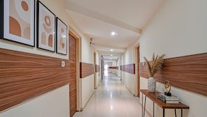 Passadís d'hotel amb panells de fusta, obres d'art als murs i una petita taula amb objectes decoratius.