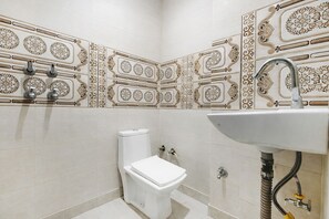 Un baño pequeño con inodoro, lavamanos y azulejos decorativos.