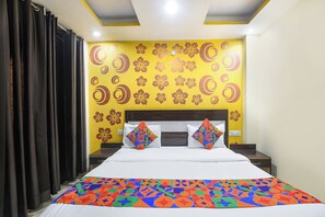 Una habitación de hotel con cama, mesita de noche y pared decorada con motivos florales y círculos.