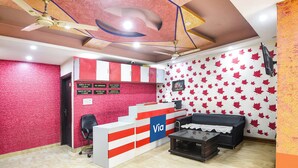 A reception area with a check-in counter, a black office chair, a small table, and a ceiling fan. - Via BD Palace (New Delhi)