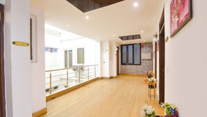 A spacious hallway with a wooden floor, a balcony with a railing, and a wall-mounted air conditioning unit. - Fabhotel 82 Inn (New Delhi)