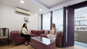 A modern interior with a purple sofa, a glass coffee table, and a large window. - Fabhotel 82 Inn (New Delhi)