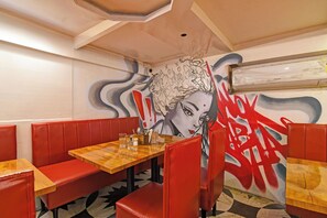 A restaurant interior with red booths, wooden tables, and a mural on the wall. - Via Kings Palace (Kolkata)