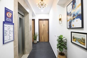 A hotel corridor with a fire evacuation plan, a lift, and a wooden door. - Fabhotel Ostan Stayz (Gurugram)