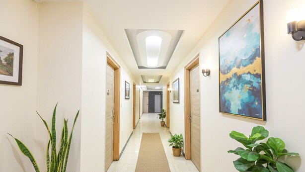 A hotel hallway with a central rug, potted plants, and framed artwork on the walls. - Fabhotel Mahal (New Delhi)