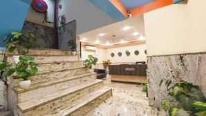 A reception area with a marble staircase, potted plants, and a reception desk. - Fabhotel Mahal (New Delhi)