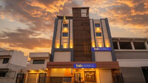 A modern building with a 'fabHOTELS' sign, featuring a prominent vertical wooden panel and multiple illuminated windows. - Fabhotel Mahal (New Delhi)
