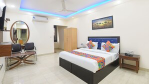 A hotel room with a bed, bedside table, and a desk with chairs. - Fabhotel Mahal (New Delhi)