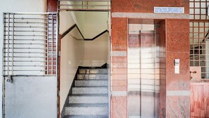 A staircase leading to an elevator in a building with a sign indicating a GSTIN number. - Fabhotel Royal Garuda Palace (Ramanagara)