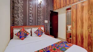 A bedroom with a bed, pillows, a nightstand, and a wardrobe. - Fabhotel Address 24 Suites (Bengaluru)