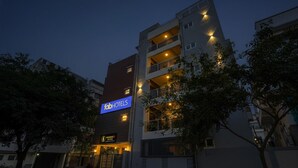 A multi-story building with a 'fabHOTELS' sign, indicating it is a hotel. There are multiple balconies and a visible entrance with a door. - Fabhotel Address 24 Suites (Bengaluru)