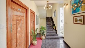 A hotel lobby with a wooden door, a staircase, and a red carpet. - Fabhotel Address 24 Suites (Bengaluru)