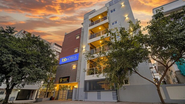 A multi-story hotel with a prominent 'FabHotels' sign, a parking garage, and a gated entrance. - Fabhotel Address 24 Suites (Bengaluru)
