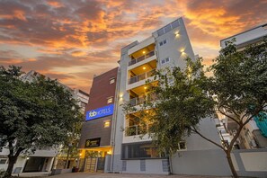 A multi-story hotel with a prominent 'FabHotels' sign, a parking garage, and a gated entrance. - Fabhotel Address 24 Suites (Bengaluru)