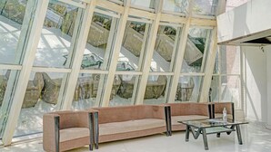Um interior moderno com parede de vidro, sofá marrom e mesa de centro de vidro.