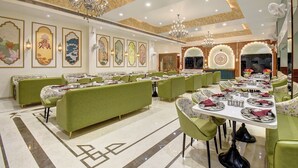 Un comedor amplio con cabinas tapizadas en verde y mesas dispuestas para comer.