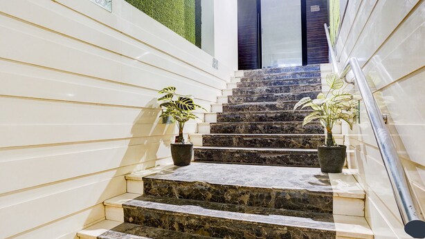 A staircase with marble steps, white walls, and potted plants. - Fabhotel Abrol Suites (Mumbai)