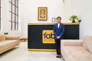 Ein Empfangsbereich mit einem schwarzen und gelben Schild mit der Aufschrift "fab hotels", einem gerahmten Kunstwerk an der Wand und einem Blumentopf auf einer Theke.