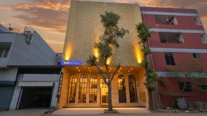 Um edifício com uma placa da 'FabHotels' e uma árvore na frente.