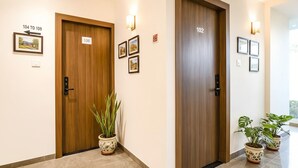 A hotel hallway with two wooden doors, numbered 106 and 102, and potted plants on the floor. - Fabhotel Blu Mark (Indore)